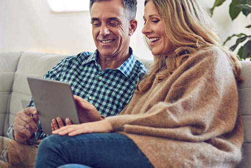 Husband and wife smiling while viewing tablet
