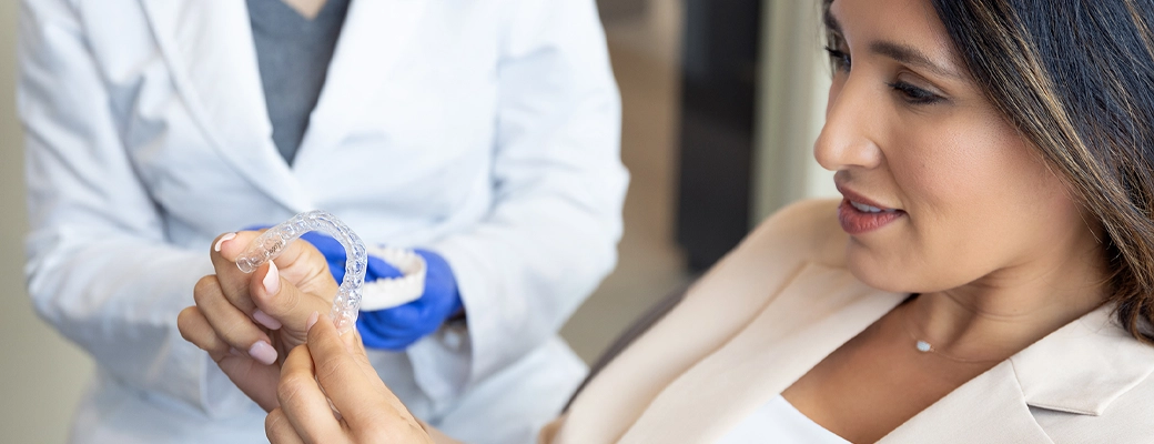 woman in dental office holding clear aligners